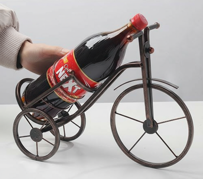 Bronze Metal Artistic Bicycle Drink Holder Stand cradling a cold drink bottle on a white dining table in Pakistan