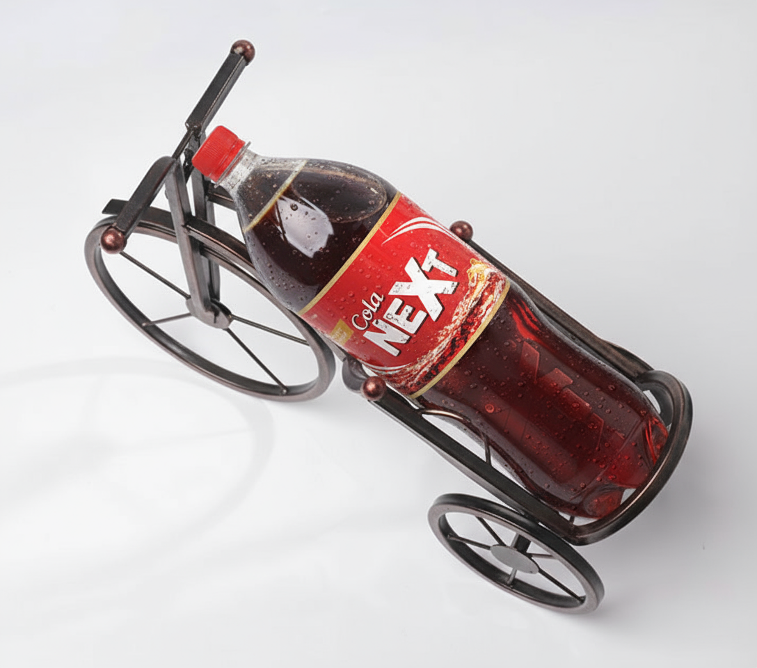 Bronze Metal Artistic Bicycle Drink Holder Stand cradling a cold drink bottle on a white dining table in Pakistan