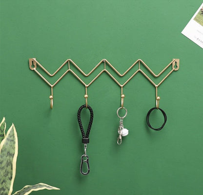 Modern gold zig-zag metal wall hook organizer with keys and accessories - Creative home decor Pakistan.